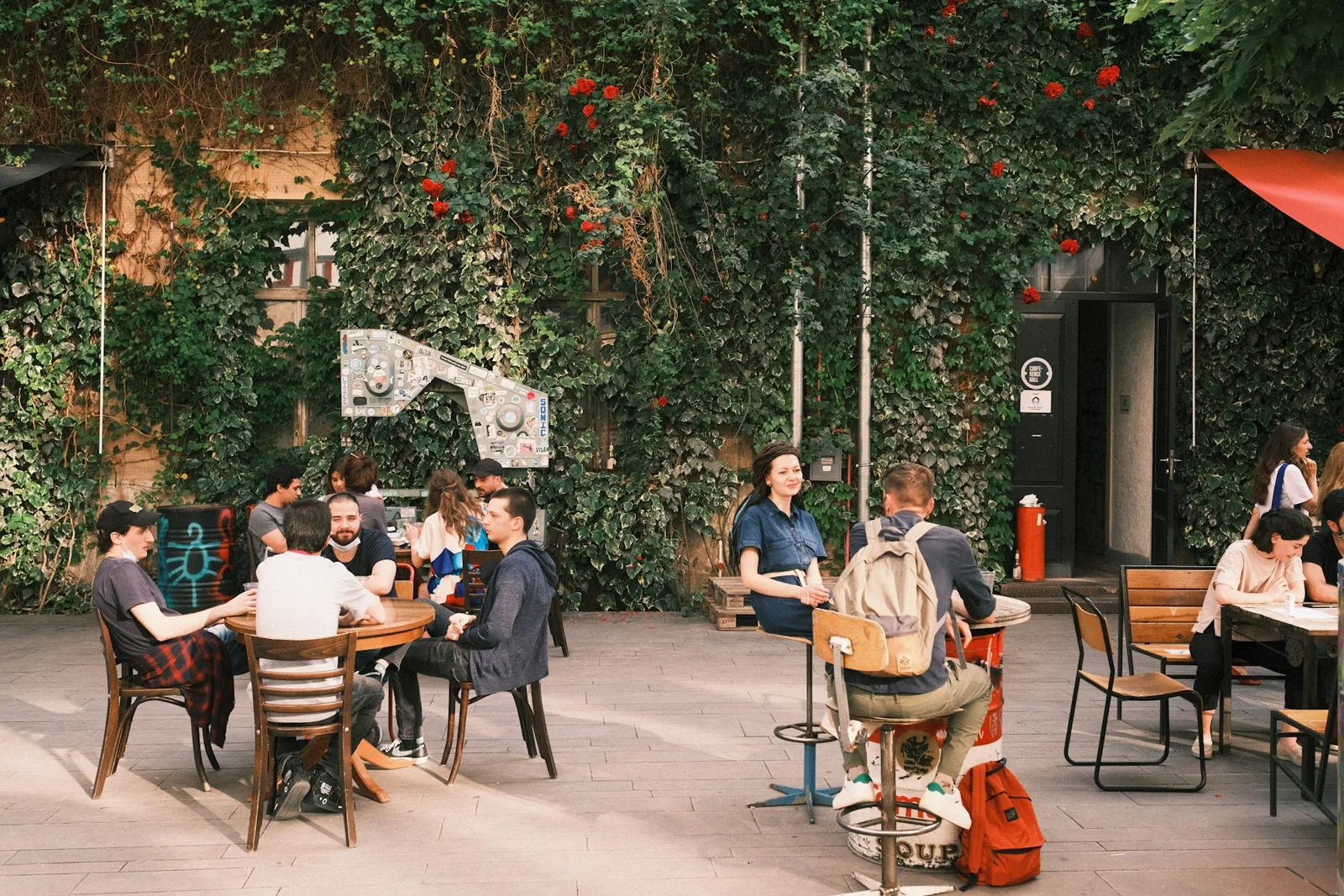 Friends talking at outdoor tables in the Fabrika courtyard in Tbilisi