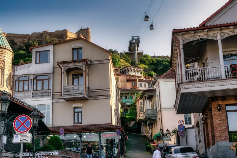 Tbilisi street life beneath carved balconies